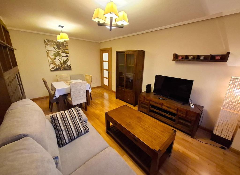 a living room with a couch and a tv and a table at Apartamento Playa Foz in Foz