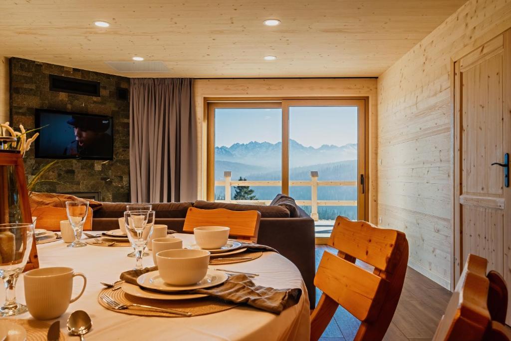 a dining room with a table and chairs with a view at Majerczyk House domki z sauną i jacuzzi in Poronin