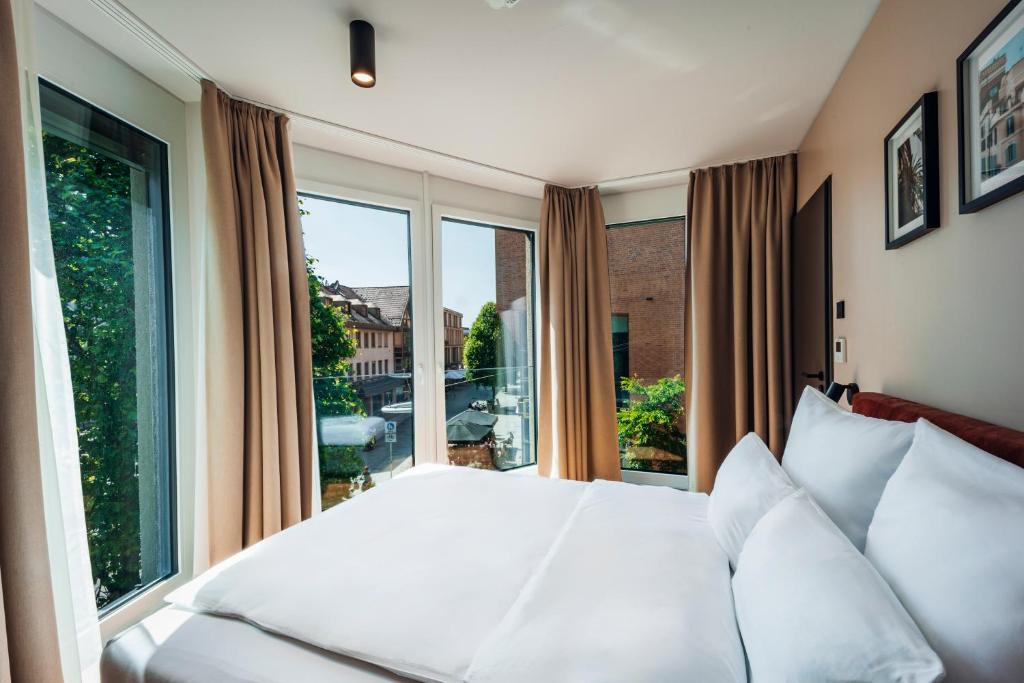a bedroom with a white bed and a large window at Brera Serviced Apartments Böblingen Sindelfingen in Böblingen