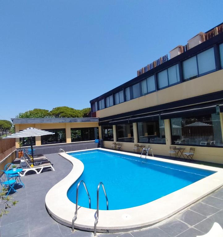 a swimming pool in front of a building at Hotel 153 in Castelldefels