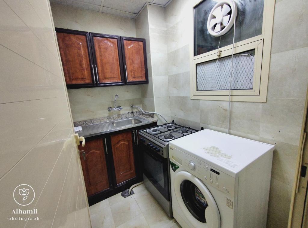 a small kitchen with a stove and a washing machine at Solo comfort stay 1 in Al Ain