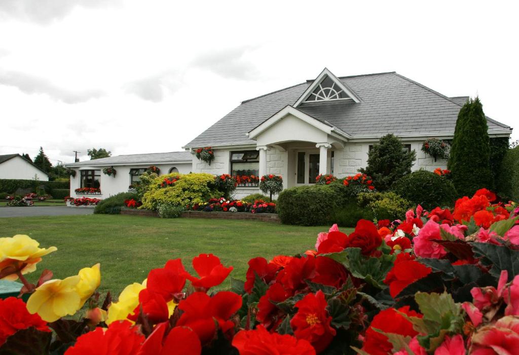 uma casa com flores vermelhas e amarelas no quintal em Rosemount B&B em Dundalk