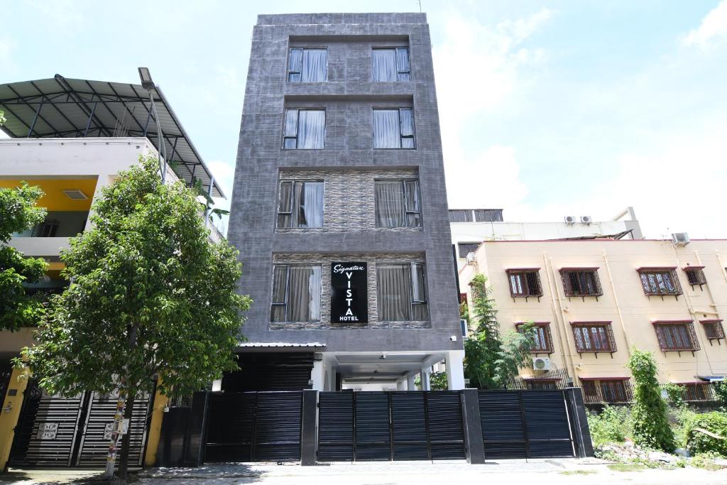 Un edificio alto y gris con una valla negra delante. en Hotel Signature Vista, en Calcuta