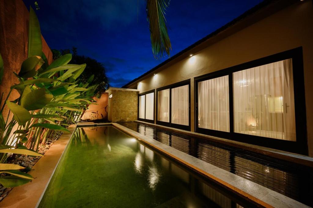 a house with a swimming pool in front of a building at Urban Villas 5BR in Legian