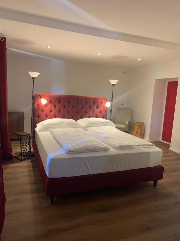 a bedroom with a large bed with a red headboard at Hotel du Lac Parc & Residence in Lavarone