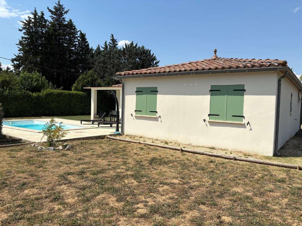 une petite maison blanche avec des portes vertes et une piscine dans l'établissement Villa 3 Chambres avec Piscine Privée, Clim, et Grand Terrain à Vallon-Pont-d'Arc - FR-1-382-52, à Vallon-Pont-dʼArc