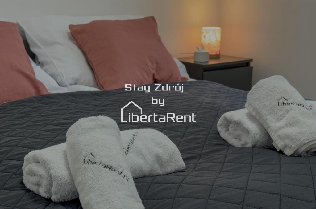 Una cama con toallas blancas con las palabras "Quédate Zril arriba inteligente". en StayZdrój by LibertaRent, en Wałbrzych