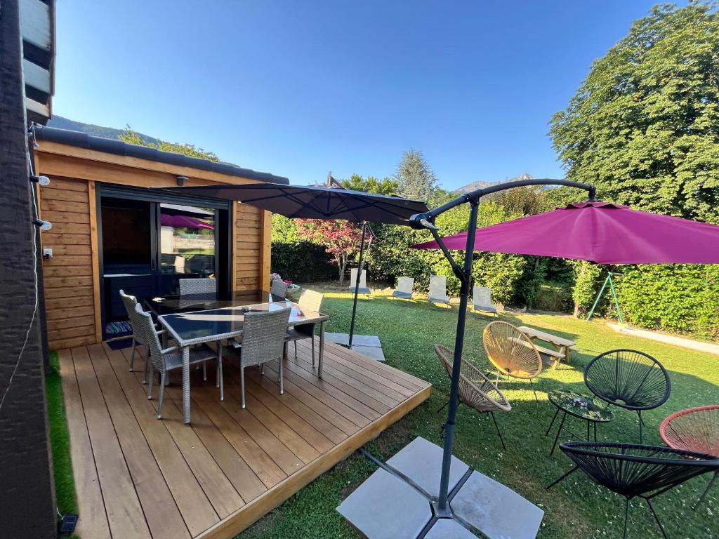une terrasse en bois avec une table et un parasol dans l'établissement Le Hourmigué maison avec jacuzzi à 15mn de Luchon, à Cierp