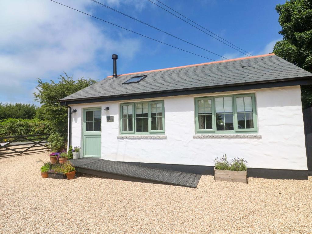 a white house with green doors on a gravel yard at Lavender Cottage in Helston