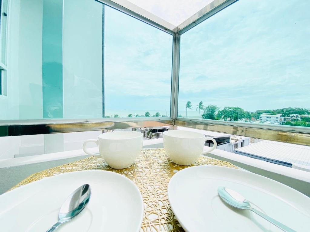 a table with two white plates and utensils on it at The Sunset Exclusive Top Floor in Chon Buri