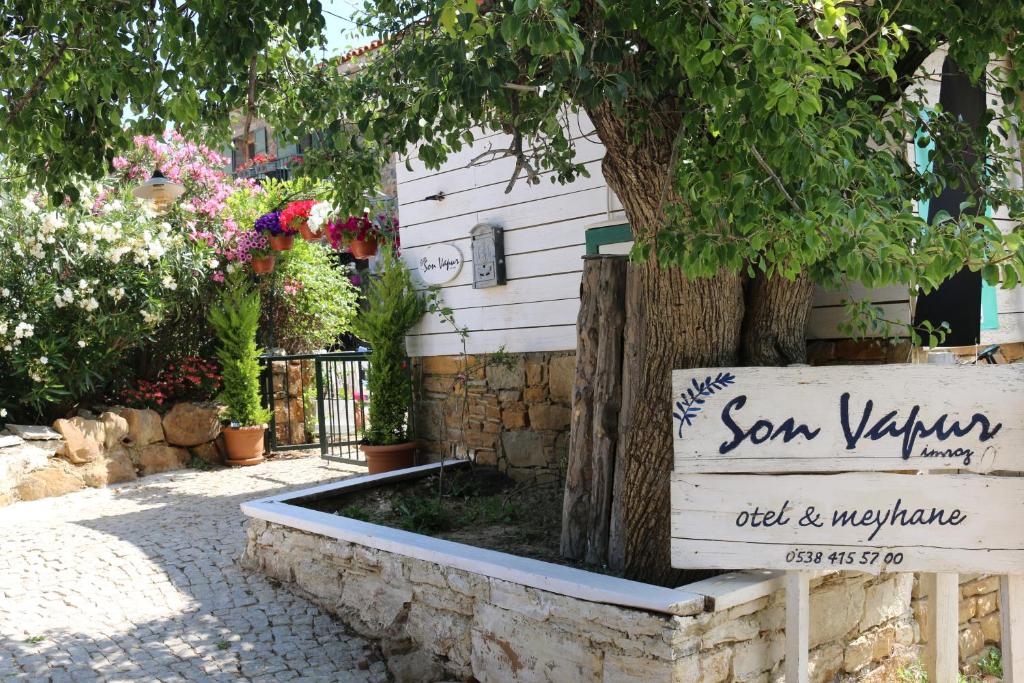 a sign in front of a building with a tree at Son Vapur Otel in Gökçeada