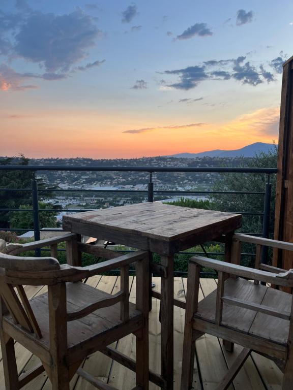 a wooden table and chairs on a balcony with a sunset at Dôme Nissaya in Nice