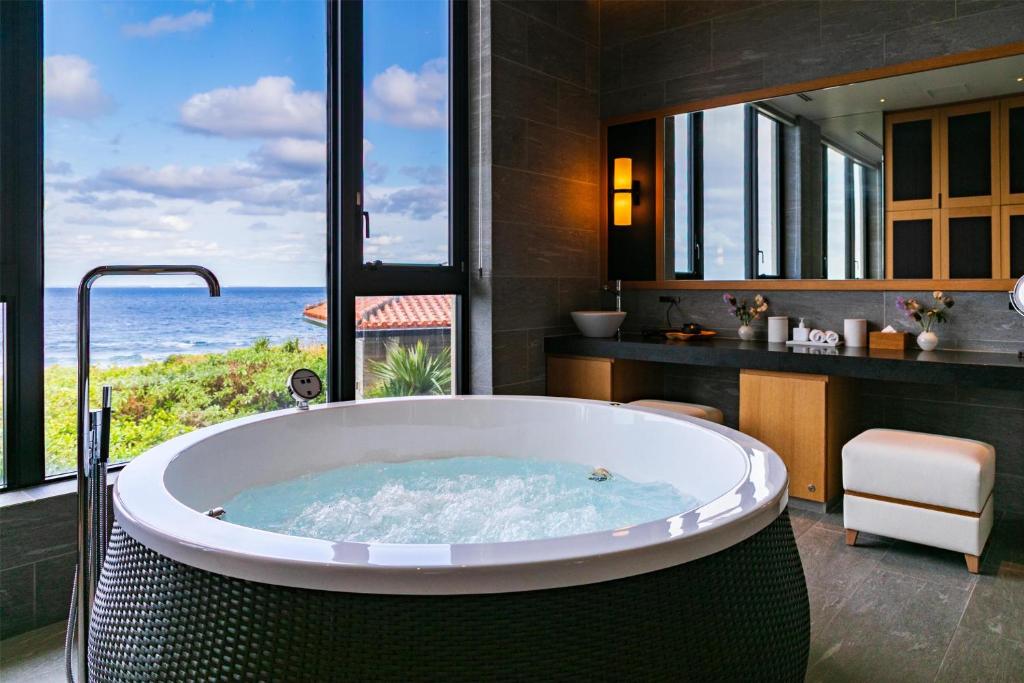 a bath tub in a bathroom with a view of the ocean at Hyatt Regency Seragaki Island Okinawa in Onna