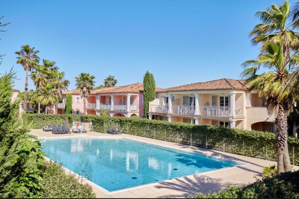 une piscine devant une maison avec des palmiers dans l'établissement L Olivier de la Palmeraie, à Grimaud