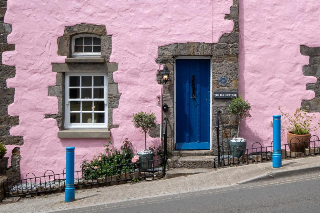 a pink building with a blue door and a window at The Old Cottage - Central Location Near the Beach in Saundersfoot