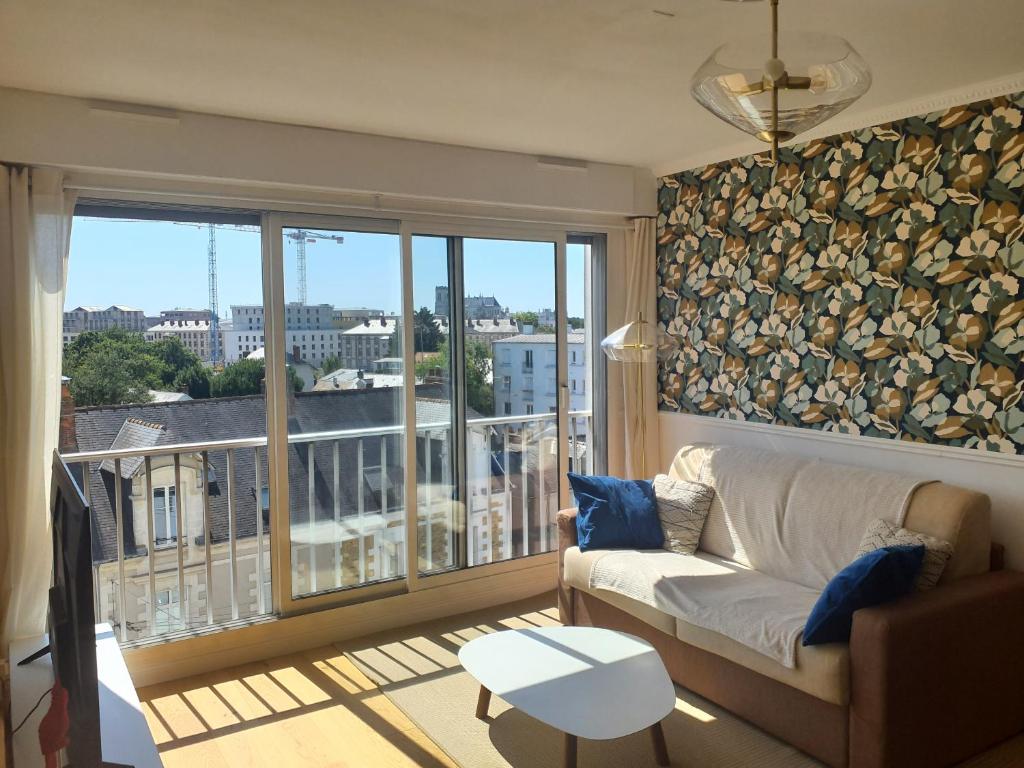 a living room with a couch and a large window at Appartement cosy Nantes proche gare in Nantes