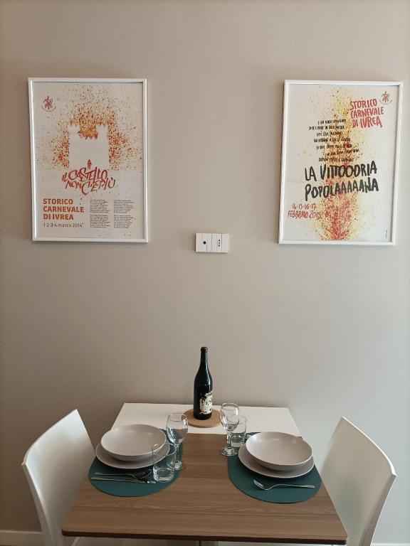 a dining room table with plates and a bottle of wine at Casa di Otti in Ivrea