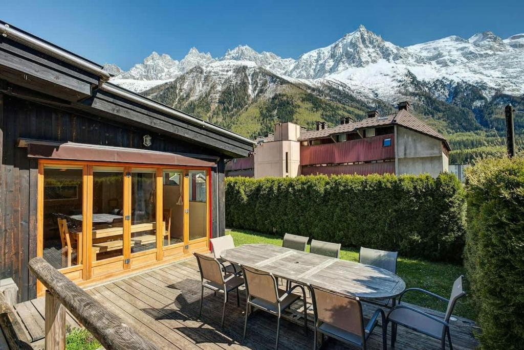 une terrasse en bois avec une table, des chaises et des montagnes dans l'établissement Chalet Alpins - Central Jacuzzi Parking, à Chamonix-Mont-Blanc