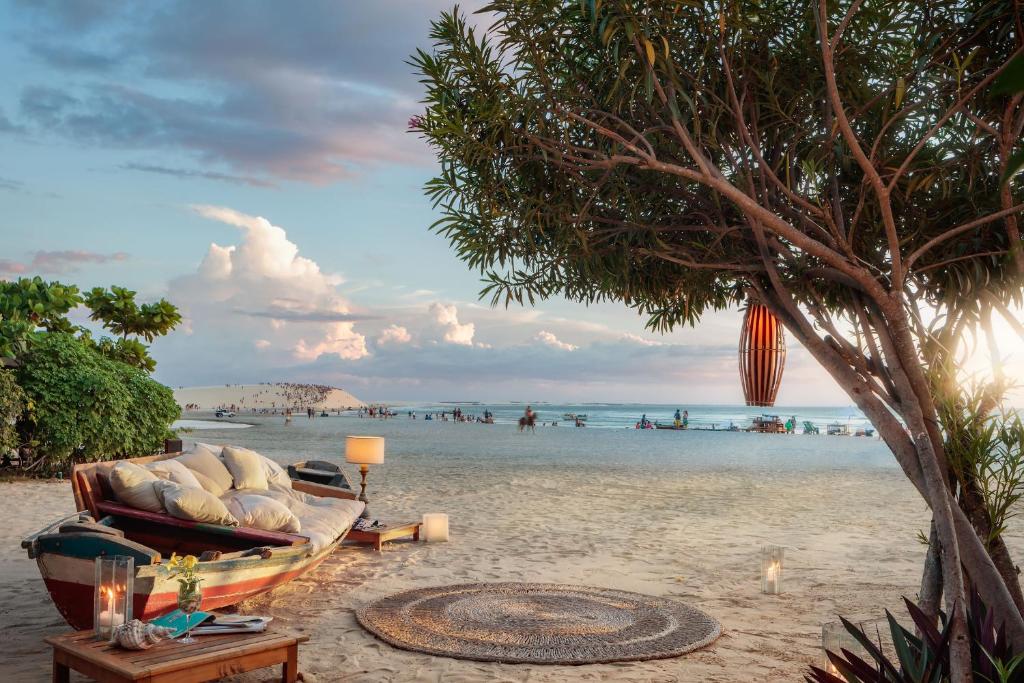 un divano su una spiaggia con un albero di Casa na Praia a Jericoacoara