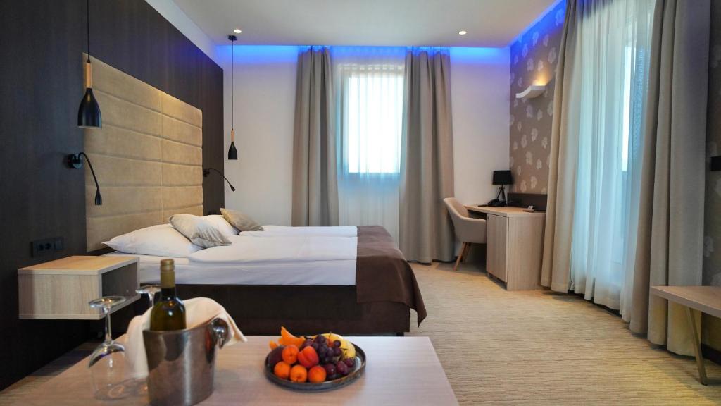 a hotel room with a bed and a bowl of fruit on a table at Hotel Gallus in Sesvete
