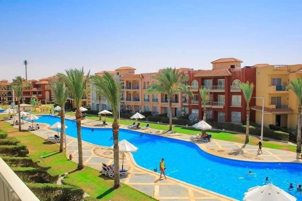 a resort with a large swimming pool with palm trees at Porto matrouh chalets for family in Marsa Matruh