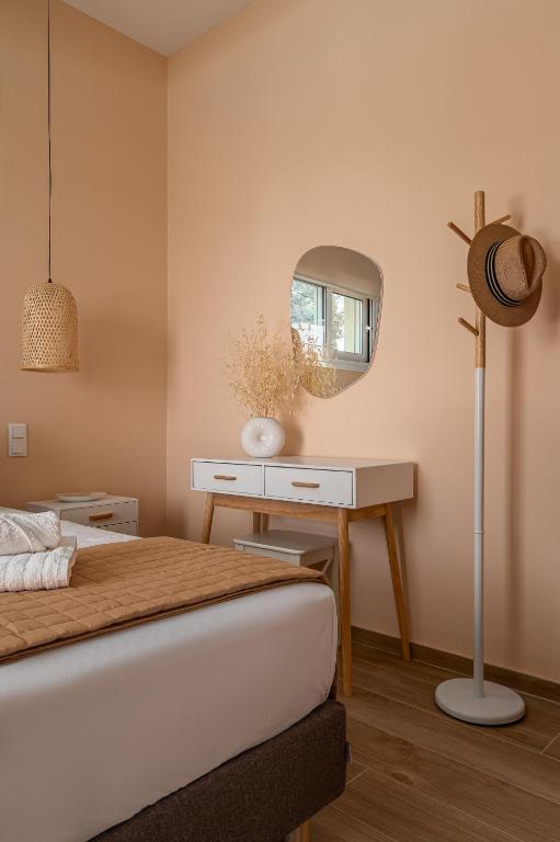 a bedroom with a bed and a table with a mirror at Dimelli Luxury Suites in Ermioni