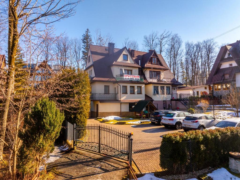 a house with cars parked in a parking lot at Pokoje u Beaty in Zakopane
