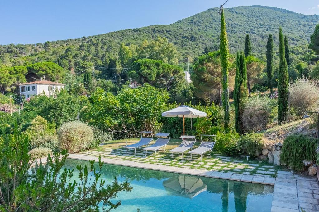 een zwembad in een tuin met stoelen en een parasol bij Villa Il Bagno in Bagno