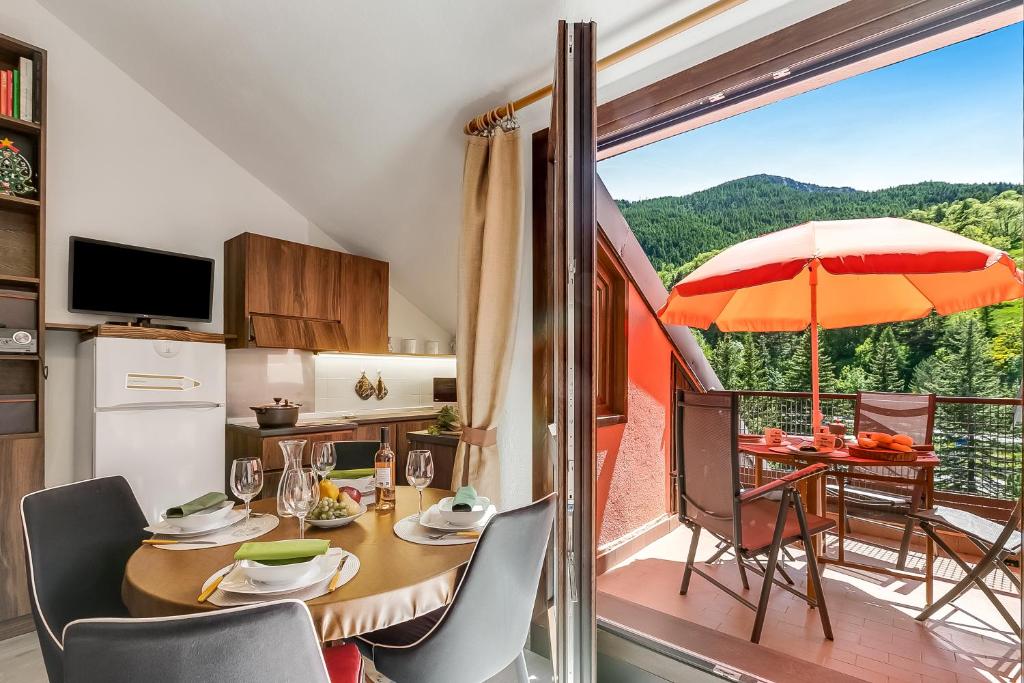a kitchen and dining room with a table and an umbrella at Appartamento Alpine Inspiration - Happy Rentals in Cesana Torinese