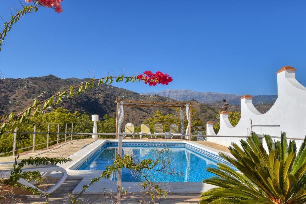 a villa with a swimming pool with mountains in the background at Casa la Flor, villa with seaview in region Malaga in Sayalonga
