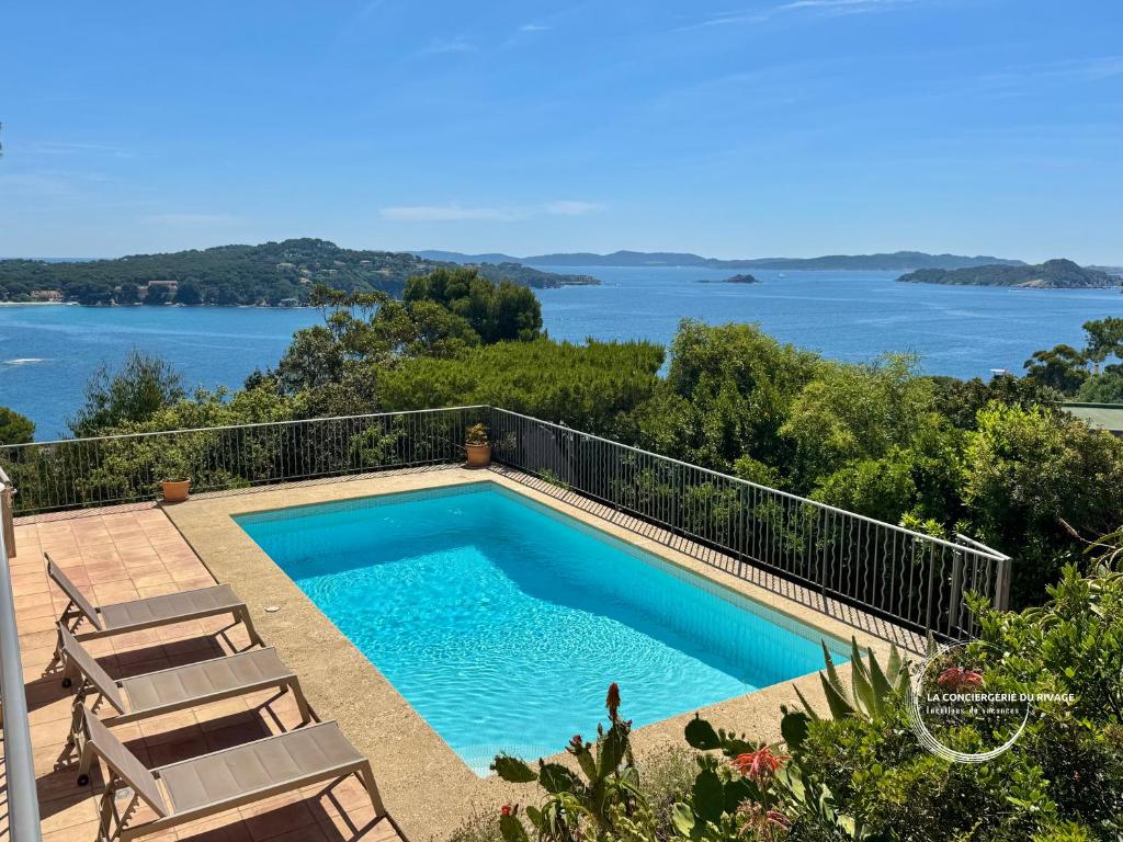 - une piscine avec des chaises et une vue sur l'eau dans l'établissement Villa La Sarrazine - Port du Niel - Vue Mer, à Hyères