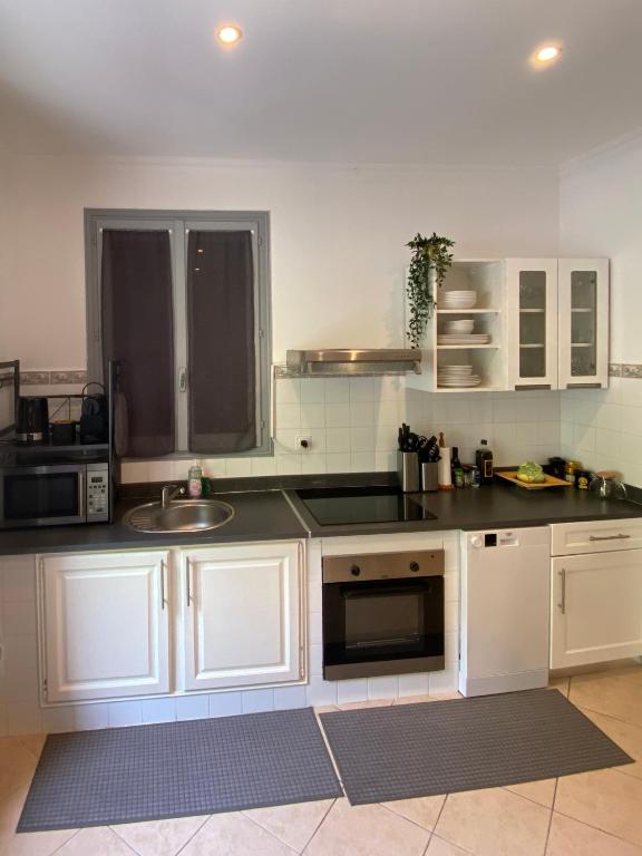 eine Küche mit weißen Schränken und einer Spüle in der Unterkunft Villa Serenice - F2 au calme, climatisé, WIFI et parking gratuit in Nizza