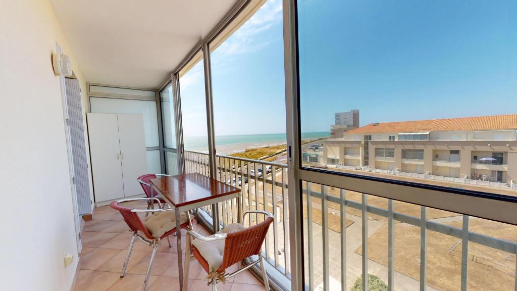 Un balcón con mesa y sillas y vista a la playa. en Cap a L Ouest, en Les Bussolleries