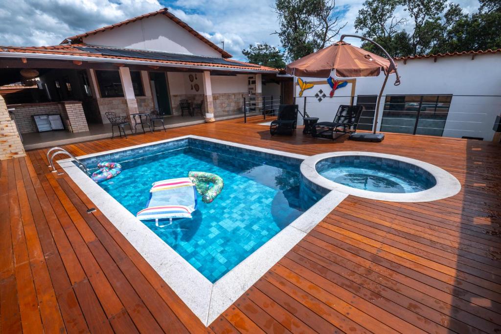 a swimming pool on a wooden deck with an umbrella at Recanto das Araras in Pirenópolis