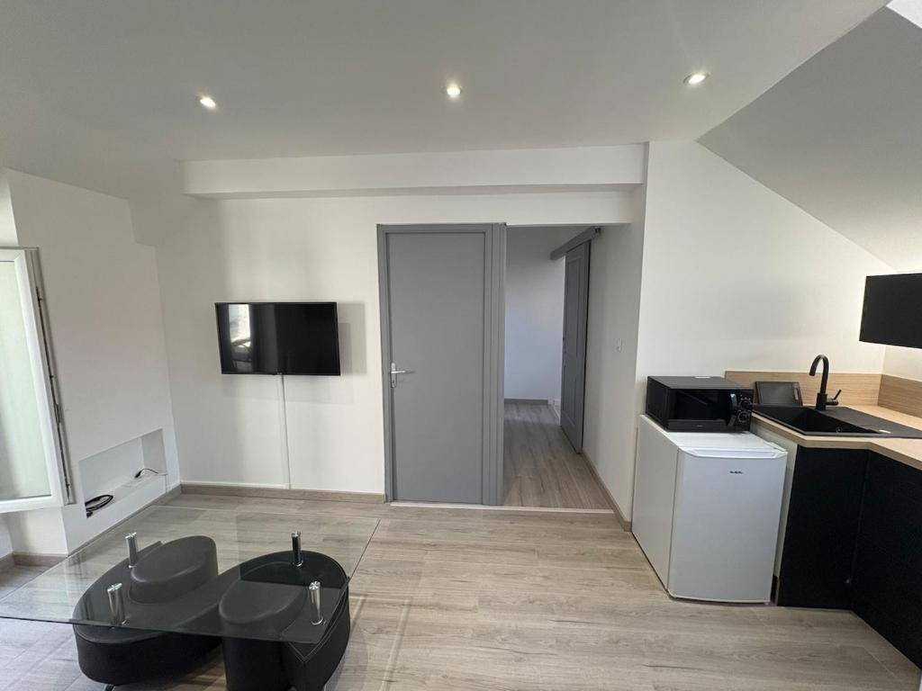 a living room with a table and a kitchen at Appartement rénové en centre-ville avec terrasse in Millau