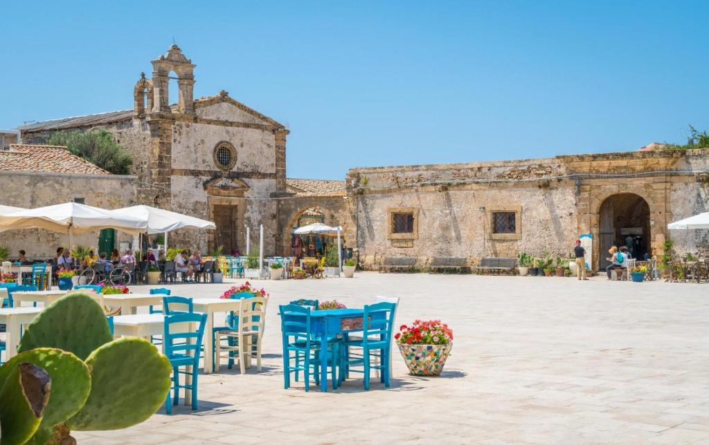 a courtyard with blue chairs and tables in front of a building at La terrazza sul mare, 44 in Marzamemi