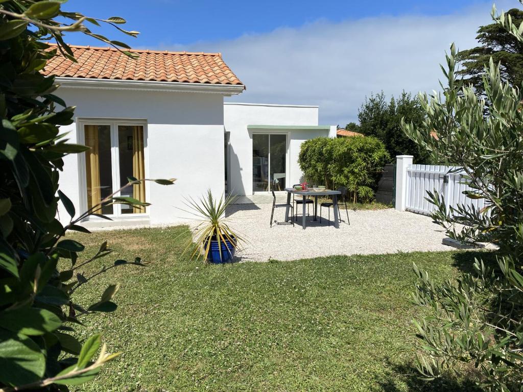 a small white house with a table in the yard at Nid douillet pour 3 à 100m de la mer in La Plaine-sur-Mer