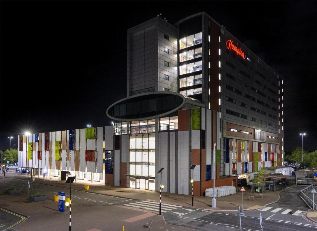 a building with a sign on the side of it at night at Hampton by Hilton Liverpool John Lennon Airport in Speke