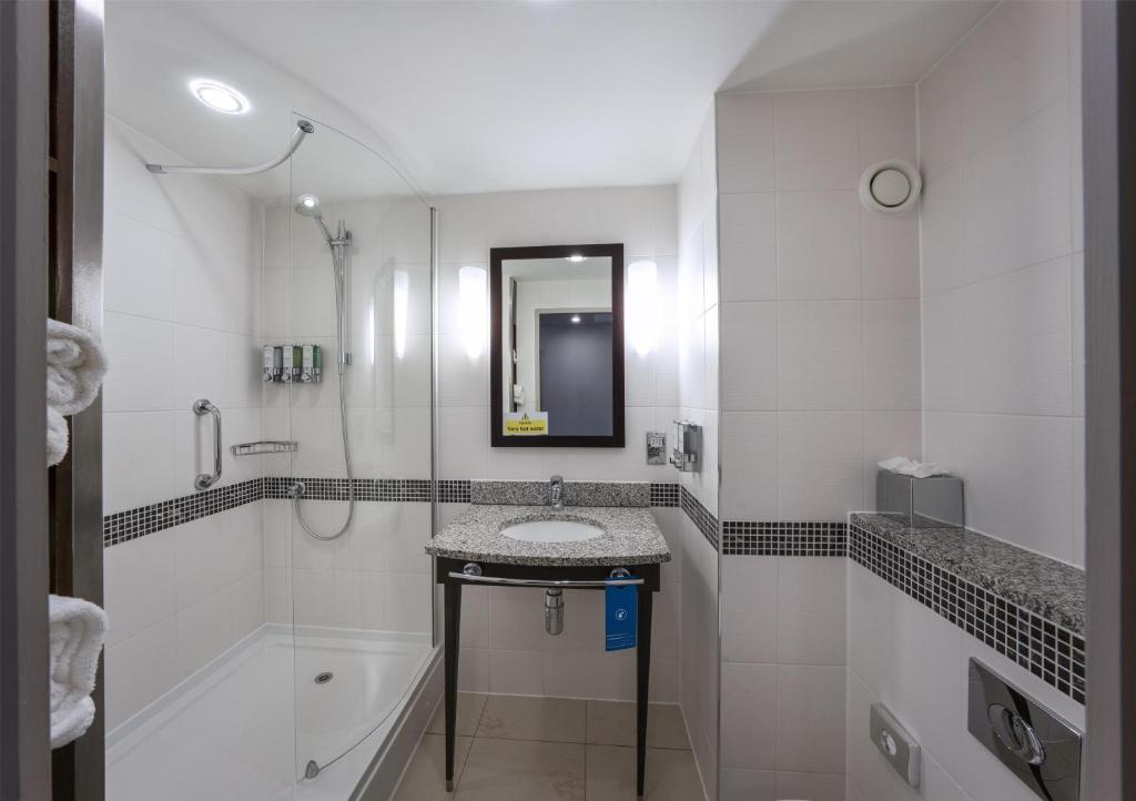 a white bathroom with a sink and a shower at Hampton by Hilton Liverpool John Lennon Airport in Speke