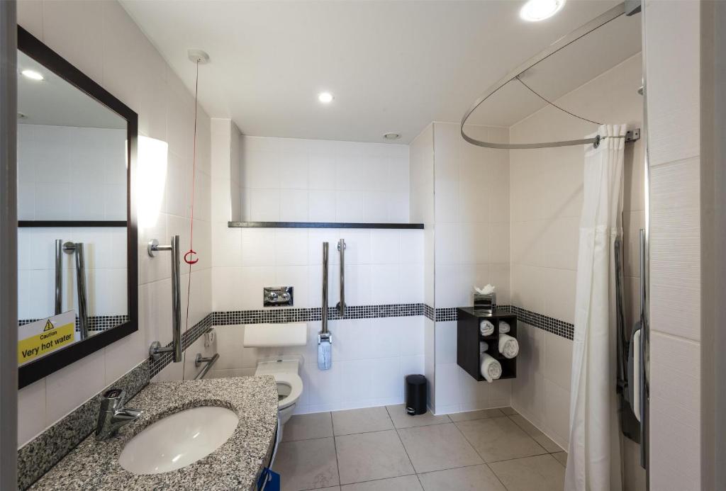 a bathroom with a sink and a toilet and a mirror at Hampton by Hilton Liverpool John Lennon Airport in Speke
