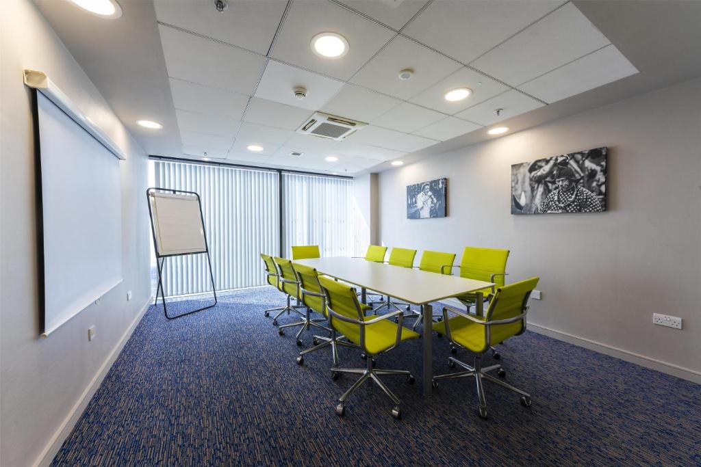 a conference room with a table and yellow chairs at Hampton by Hilton Liverpool John Lennon Airport in Speke