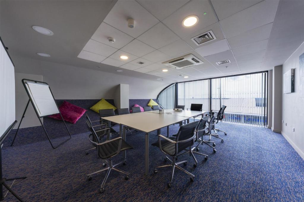 a conference room with a table and chairs in an office at Hampton by Hilton Liverpool John Lennon Airport in Speke