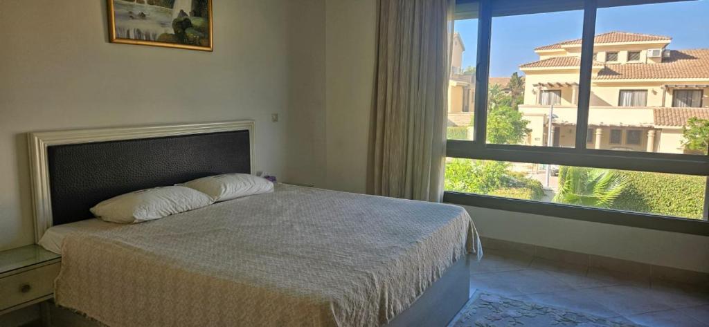 Un dormitorio con una cama y una ventana grande. en Marassi Villa Twinhouse, en El Alamein