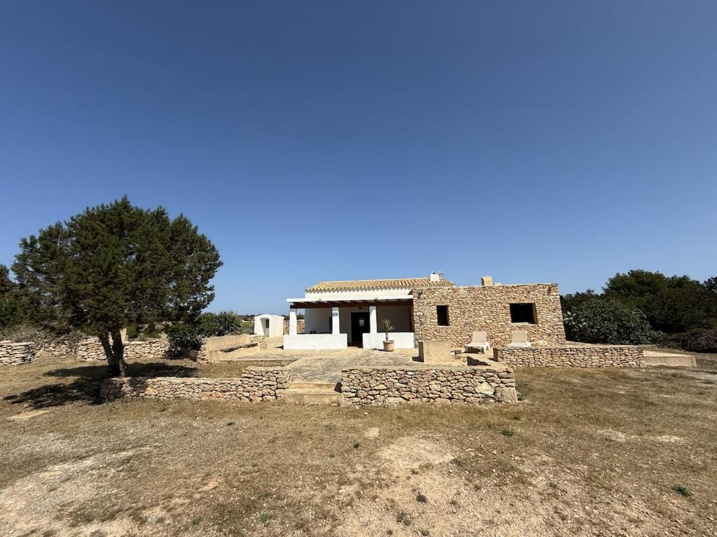 a stone house with a tree in a field at Ca Na Vilda in Sant Ferran de Ses Roques