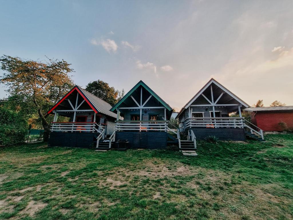 a group of three houses sitting on top of a field at Cudnie tu - Wdzydze in Wdzydze Kiszewskie