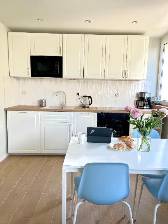 a white kitchen with a white table and blue chairs at Legnica Apartament 36m2 Delux 3 in Legnica