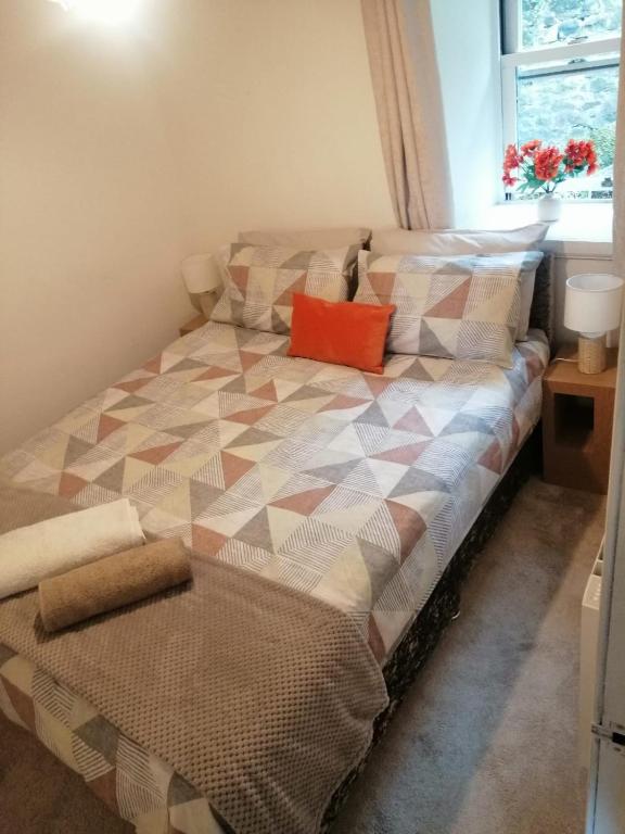 a bed with an orange pillow on it in a room at Castle Walk Apartment in Stirling