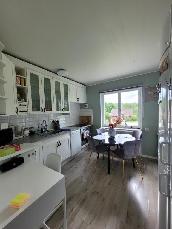 una cucina con mobili bianchi, tavolo e sedie di You Can Sleep Here a Hävla Bruk