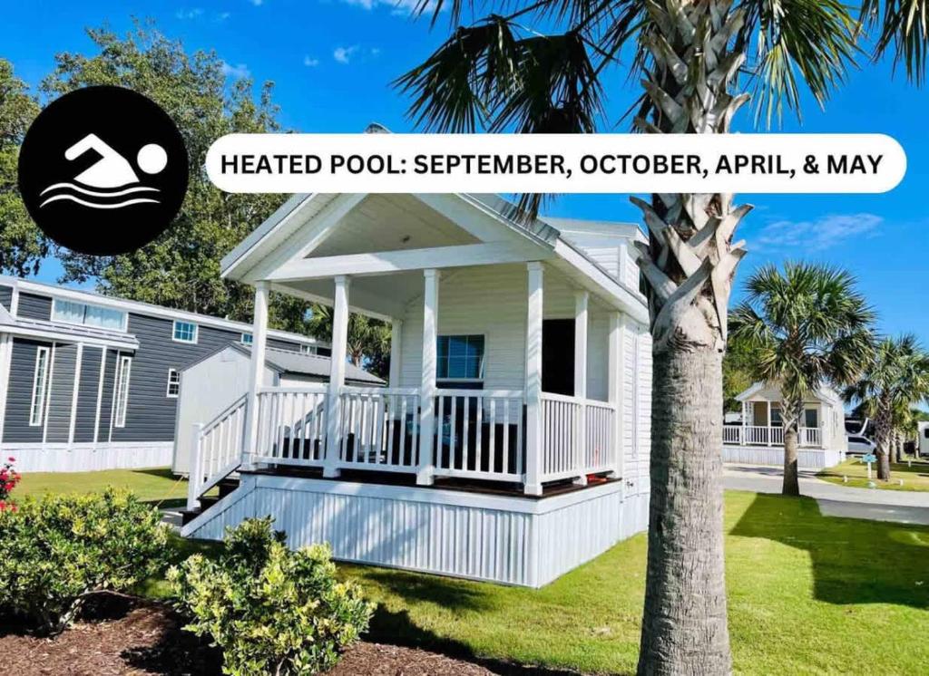 a white house with a porch with a sign on it at Vacation Cottage North Myrtle Beach #67 in Myrtle Beach