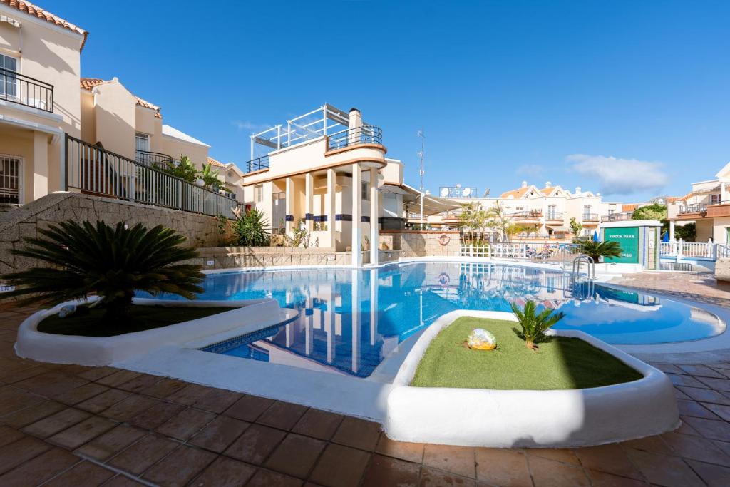 a swimming pool in front of a building with a house at Costa Adeje Fañabé Beach Apartment in Adeje